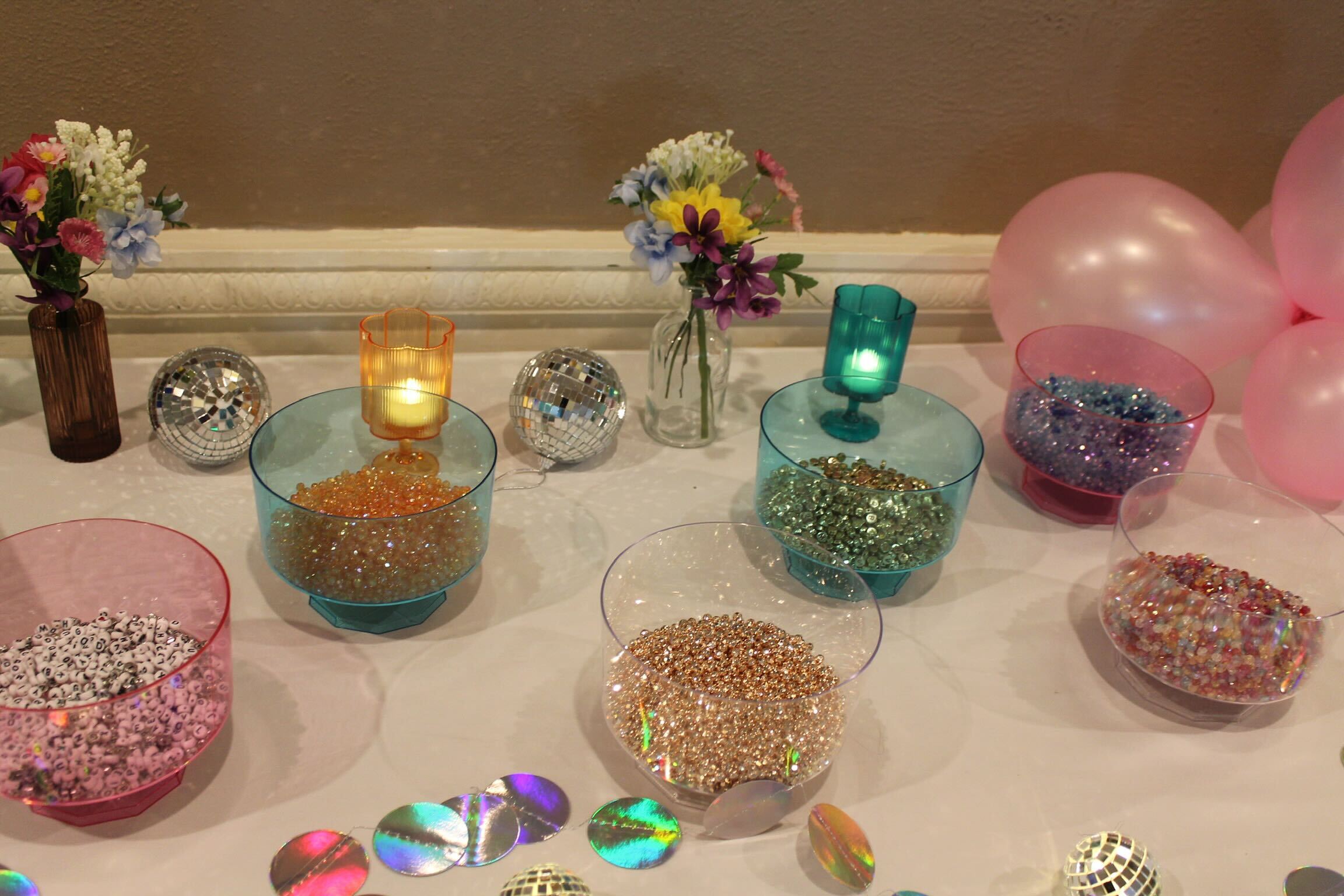 Guests making beaded bracelets at the bead bar activity table at a Mamma Mia-themed bridal shower in New Jersey

