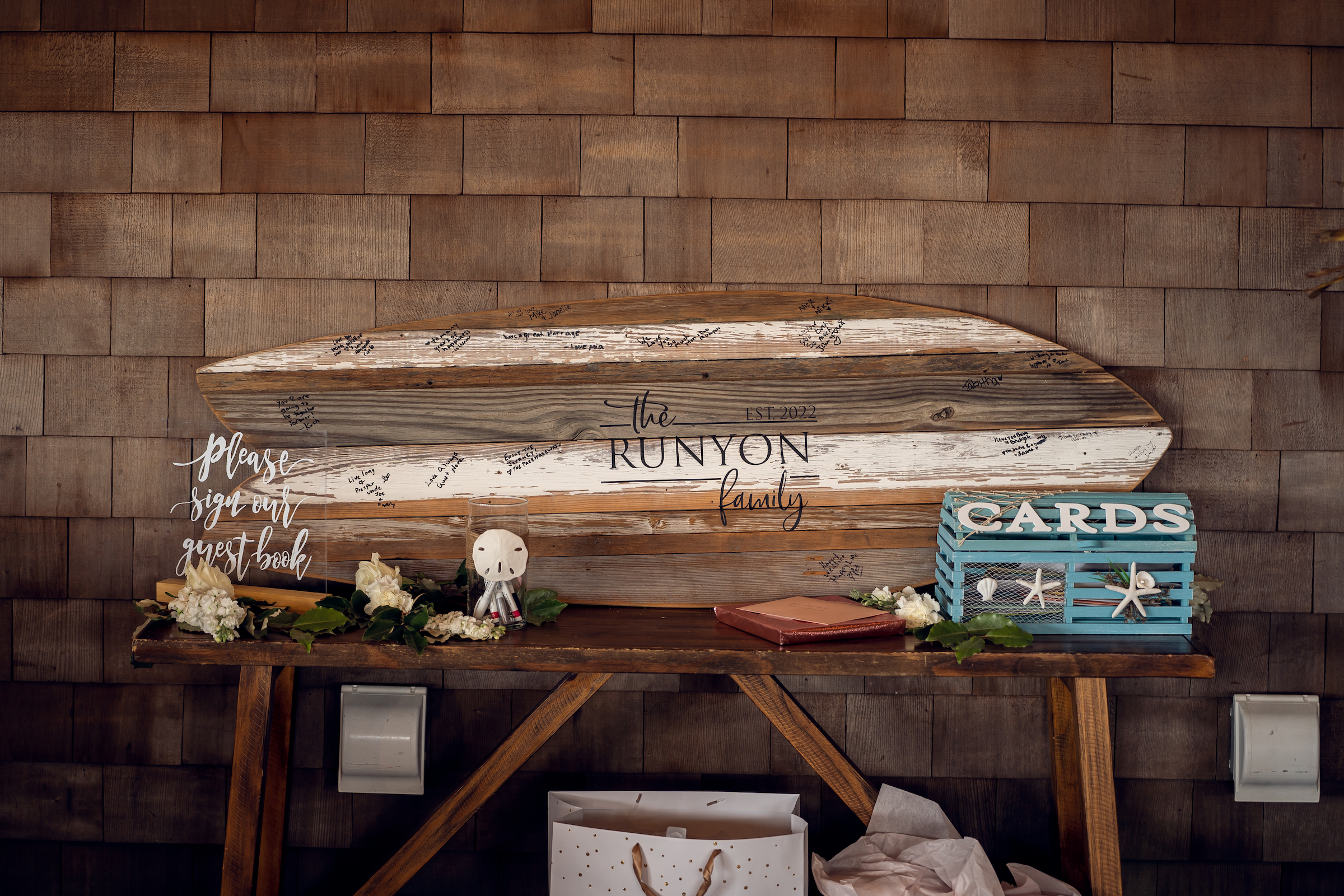 A piece of driftwood in the shape of a surfboard is the guest book for the couple's Sea Shell Resort and Beach Club wedding.