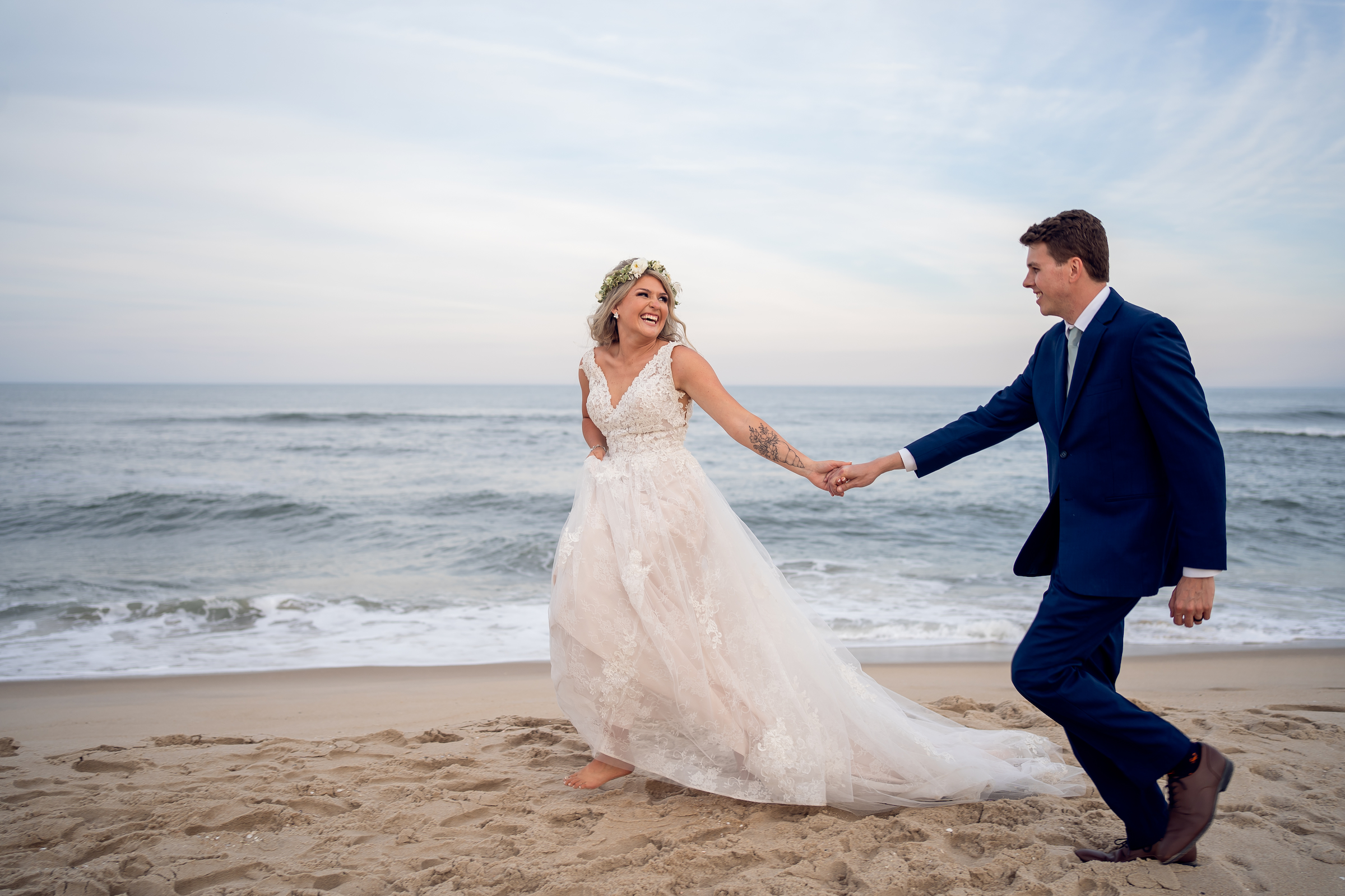 The couple holds hands and runs on the beach at their Sea Shell Resort and Beach Club wedding.