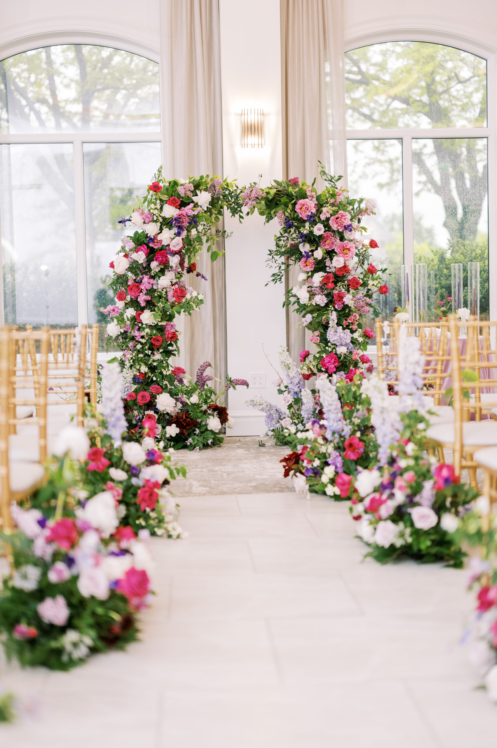 The archway and aisle in the reception room features pink, purple and white flowers as well as greenery at this Chateau Grande Hotel wedding.