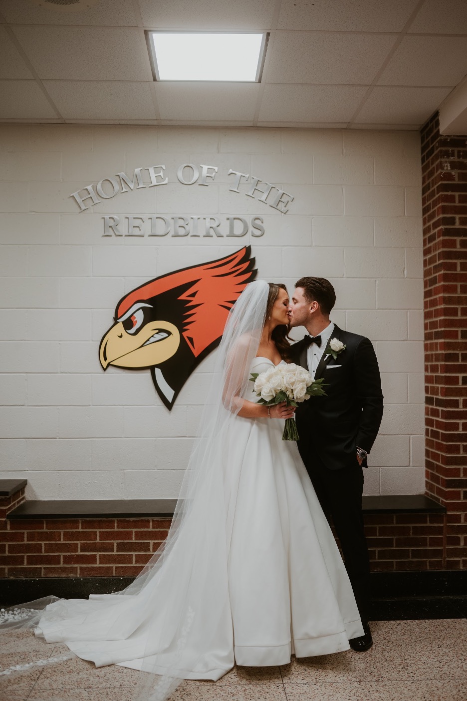 The bride and groom make a pitstop at their high school, where they met, on their wedding day.