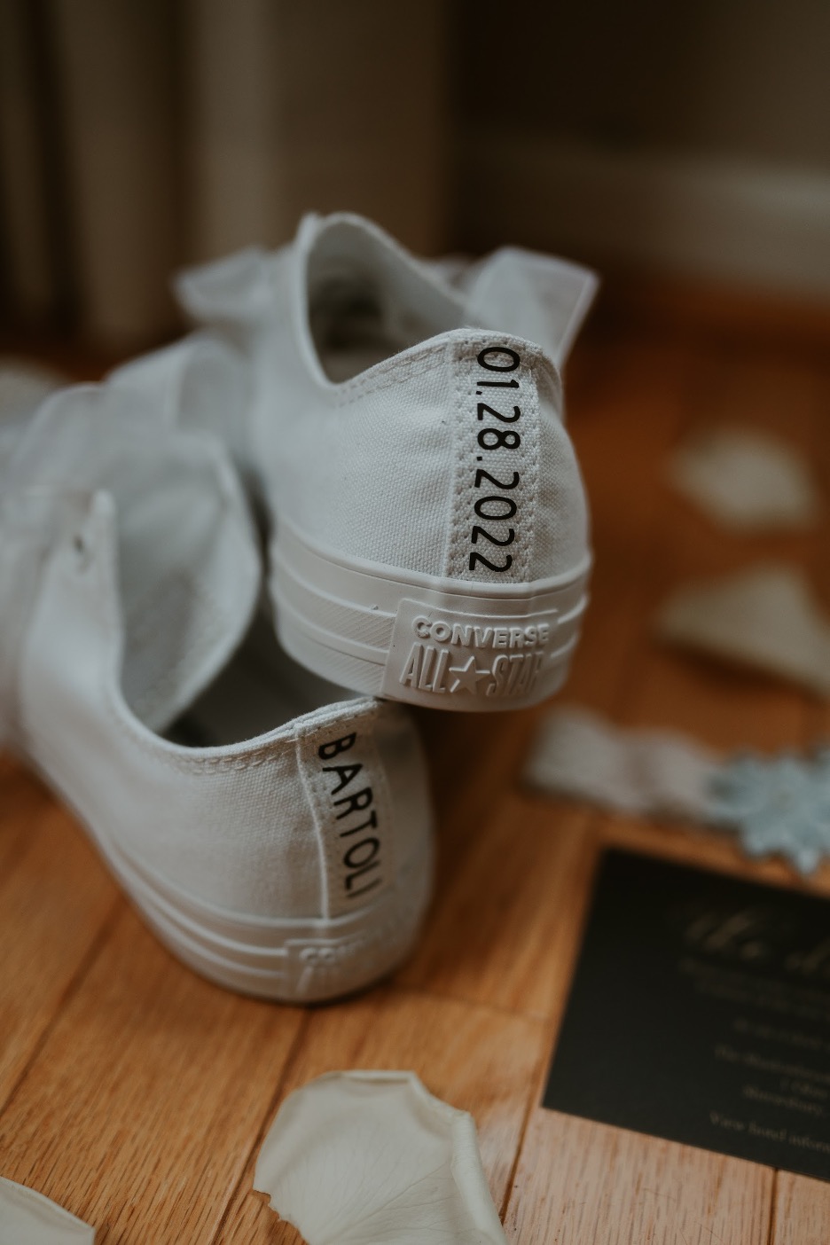 The back of the bride's white sneakers features her new last name and their wedding date.