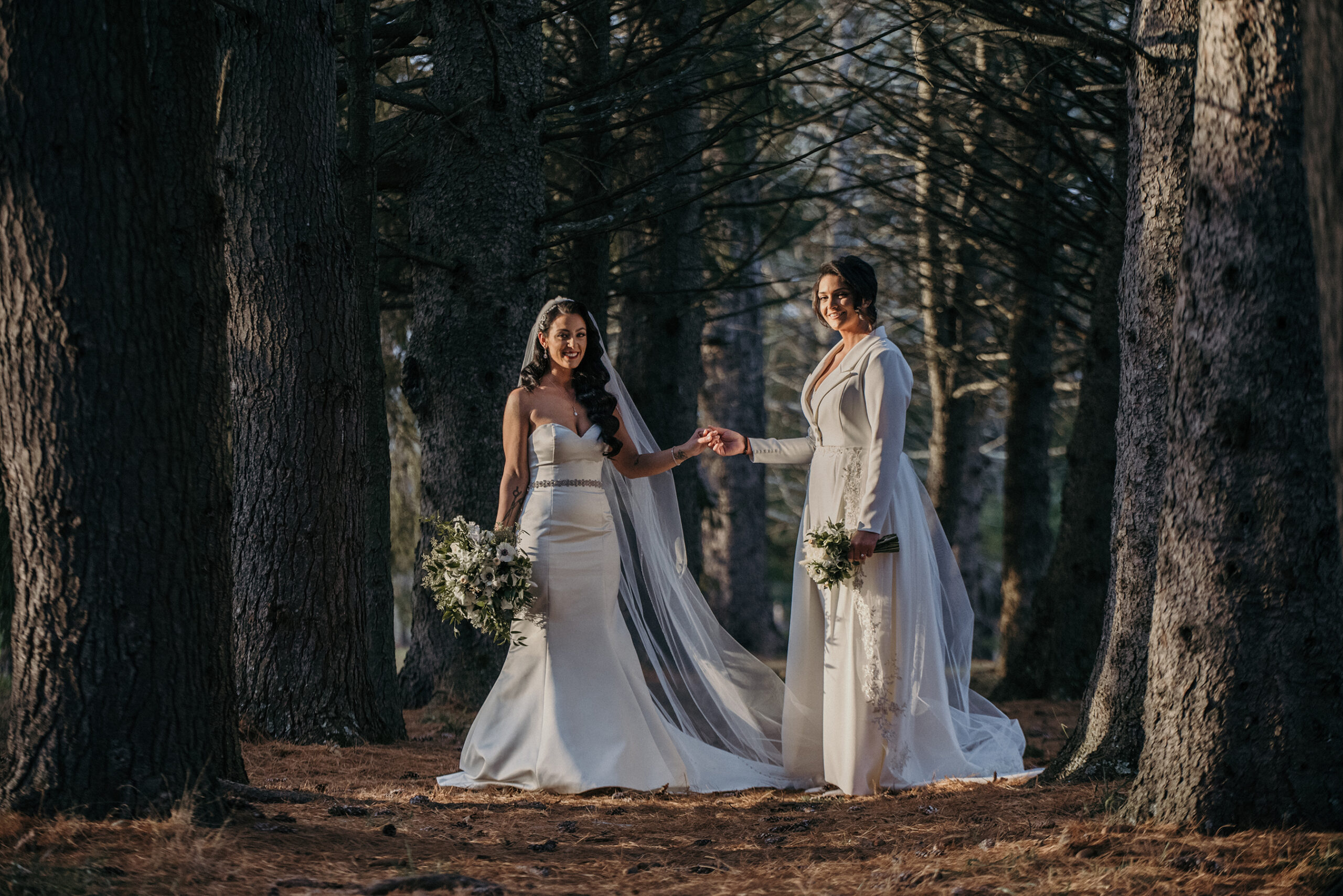 The brides in the forest on the grounds of the venue before their Perona Farm wedding.