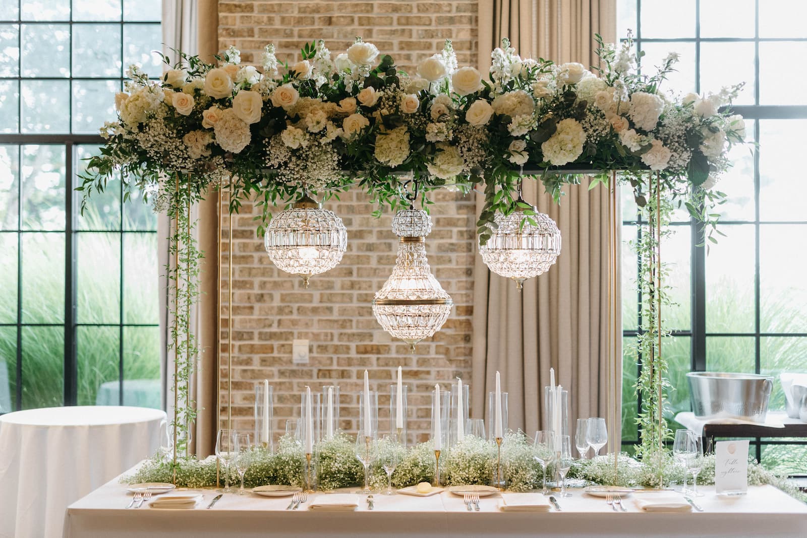 Above the sweetheart table is decorated with flowers and hanging crystal lights.