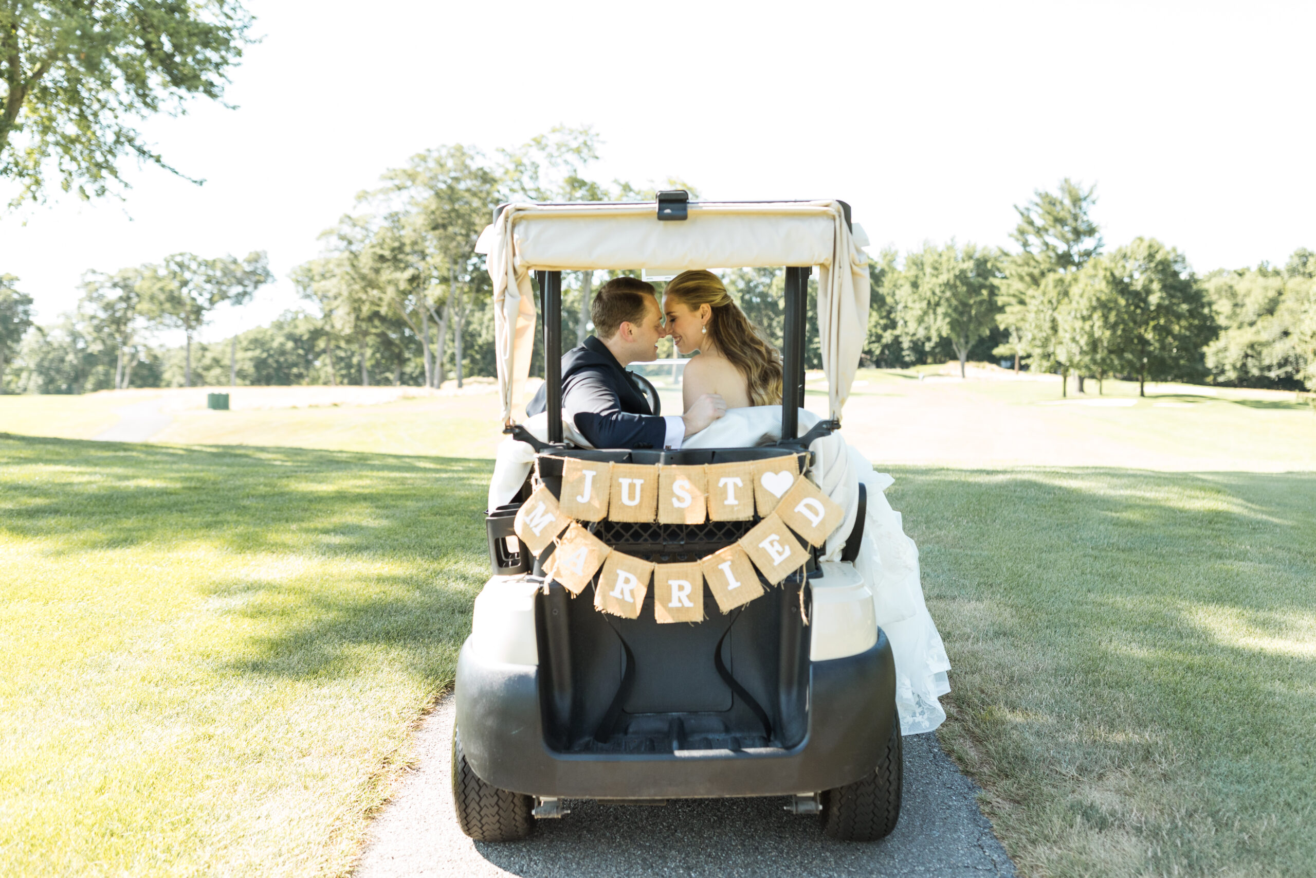A couple in a golf cart with a Just Married sign on the back at Edgewood Country Club.