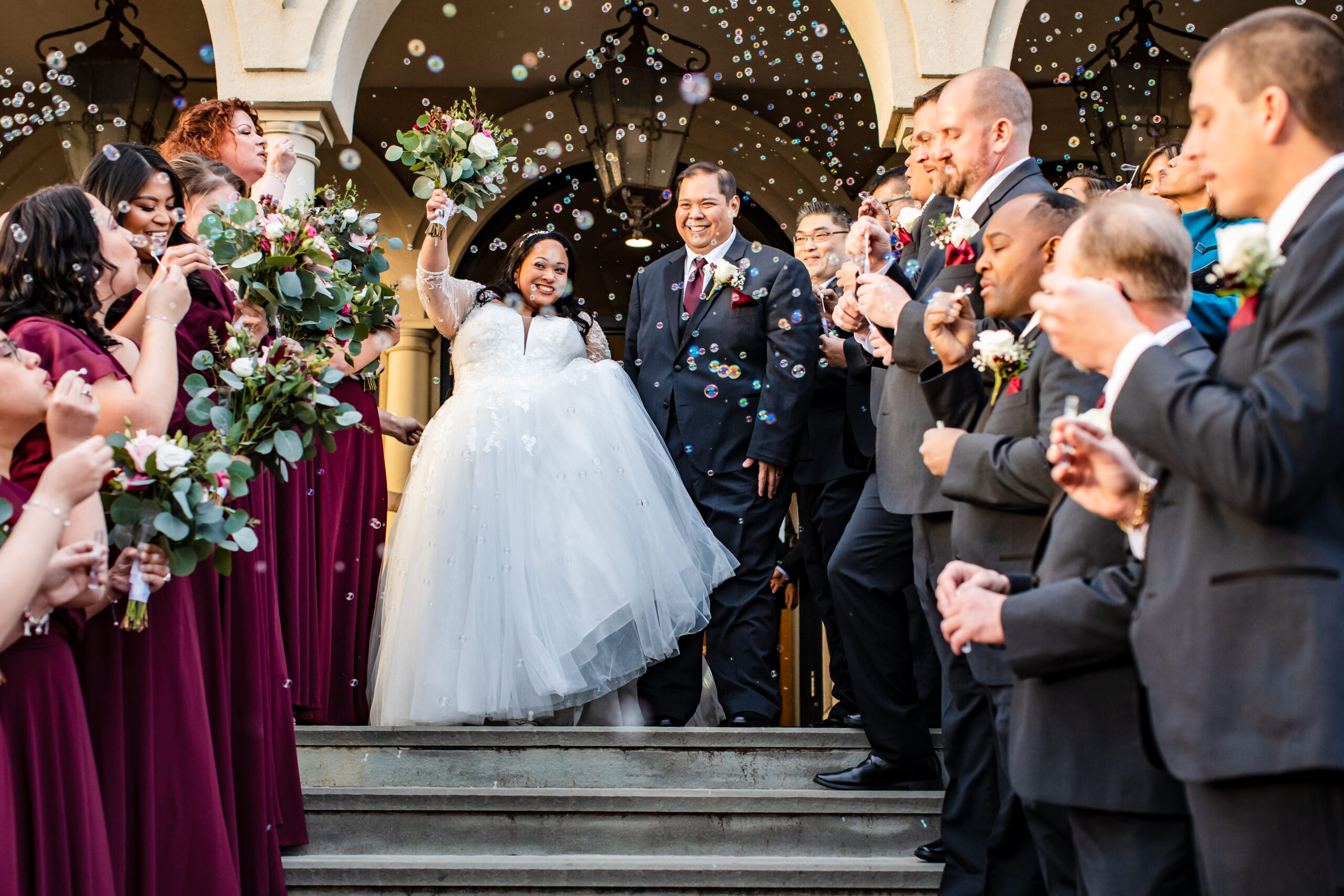 The couple exits their ceremony as guests blow bubbles.