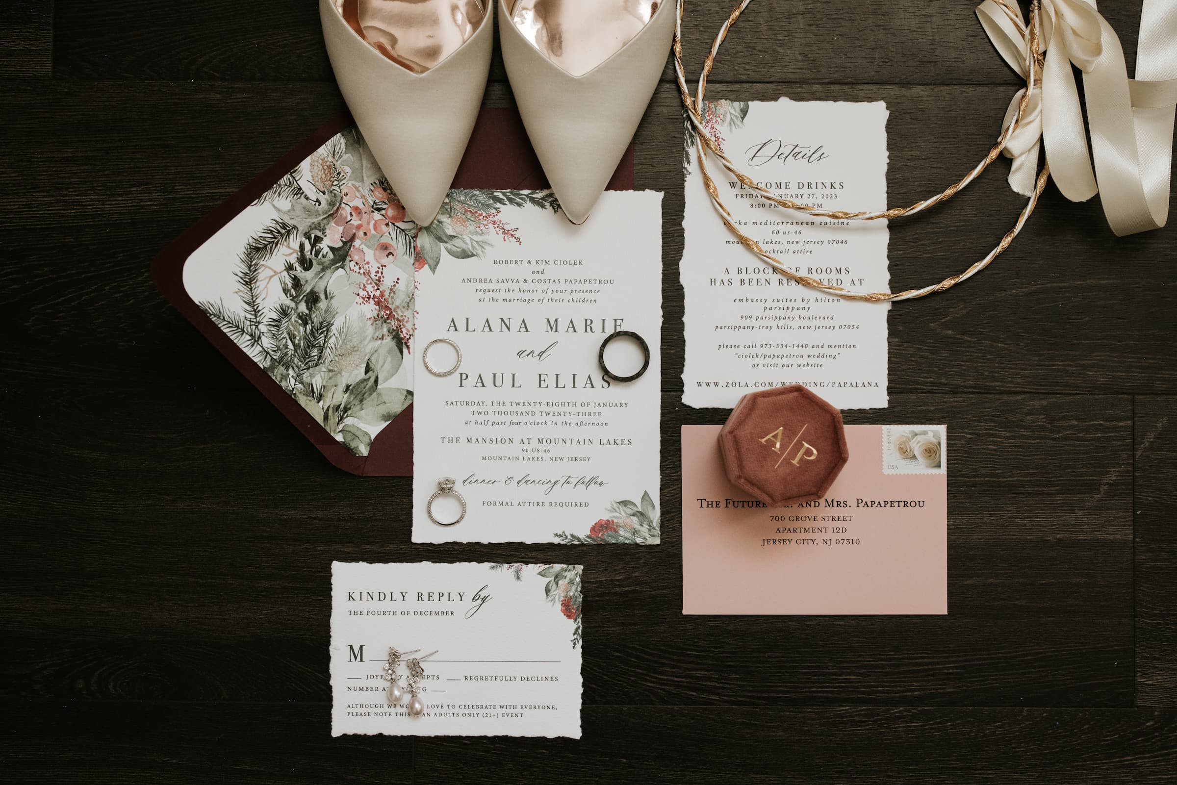 A detail shot of wedding stationary laid flat on a surface with the rings, ring box, shoes and other props on top.