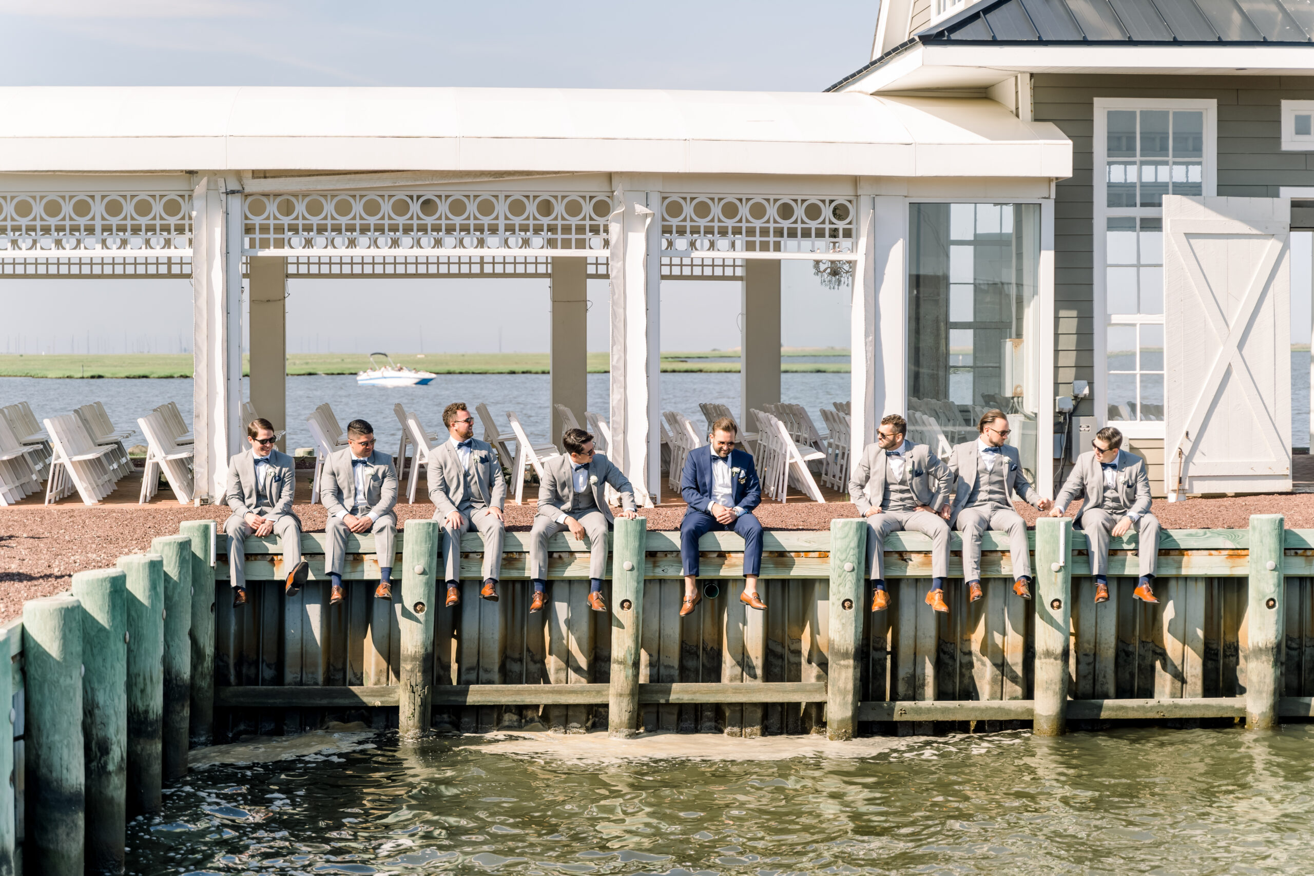 The groom and his groomsmen sit on the dock at Mallard Island Yacht Club.