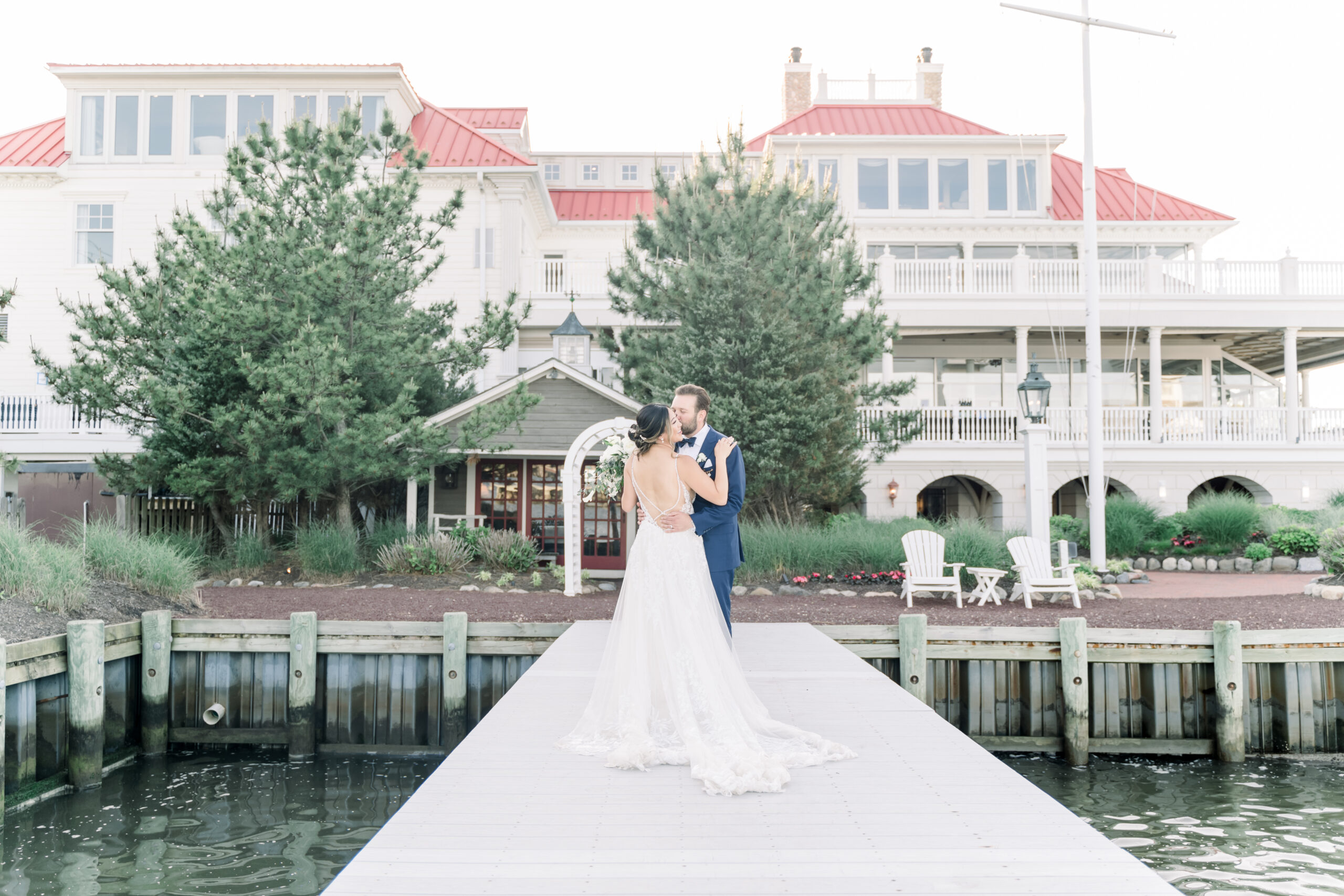 The bride and groom pose on a dock outside the Mallard Island Yacht Club.