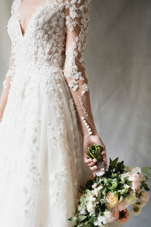 Justin Alexander Warshaw embroidered notes in Kelsey Tuchi's wedding outfits. One, on the arm of her ceremony gown reads "love, yours."