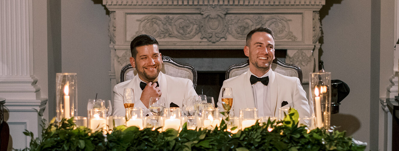 The grooms at their grooms table for two with greenery and many candles at their Park Savoy Estate wedding.