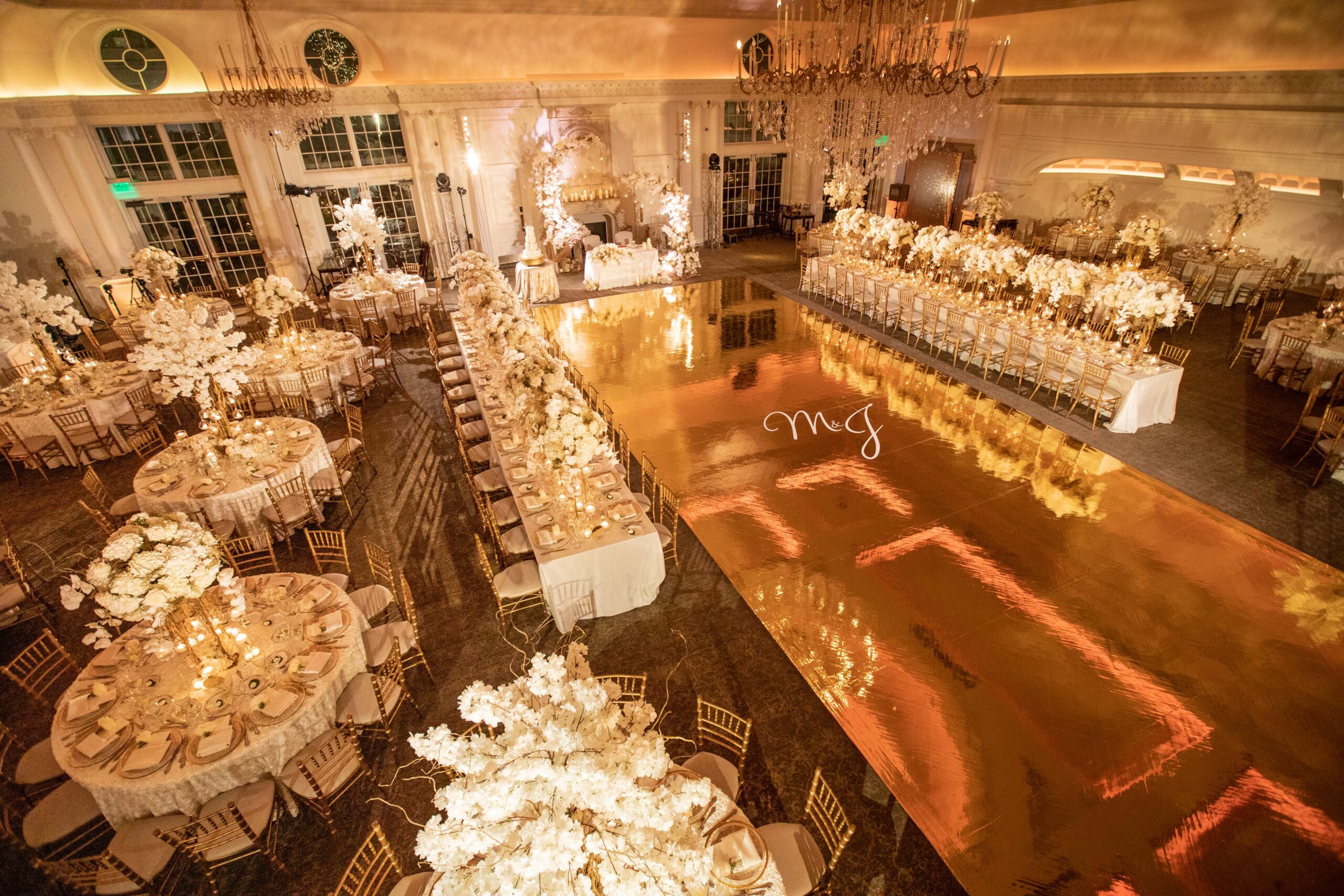 A reflective dance floor and all-white flower centerpieces set the scene for this Park Chateau wedding.
