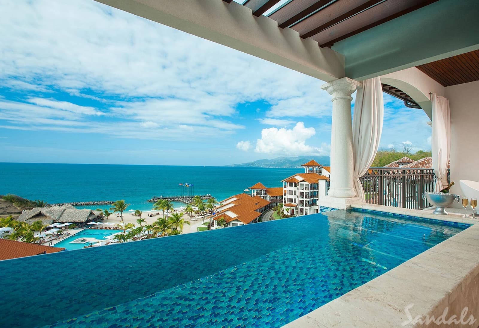 A bight blue sky, a view of Granada from behind a blur infiniti pool covered by an awning.