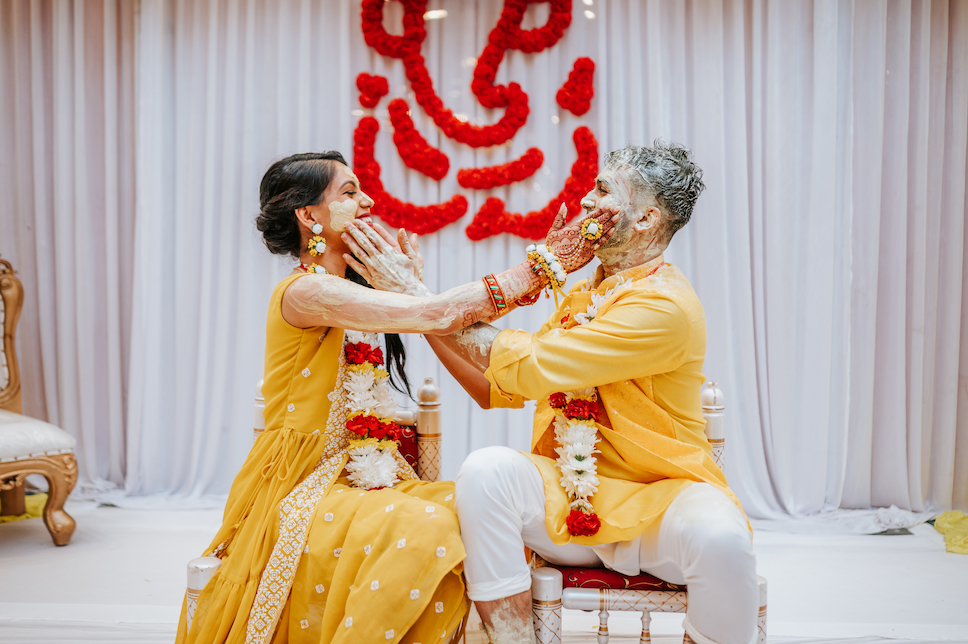 The bride and groom don yellow outfits and smear turmeric paste on each other in this photo op in the days leading up to their Indian wedding at Westmount Country Club.