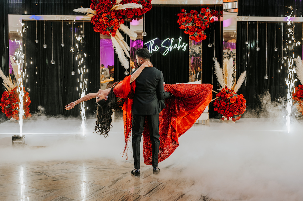 The groom in black dips the bride in red on the dance floor at their Westmount Country Club wedding.